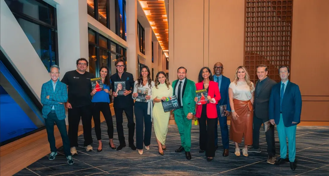 A group of guests in bright suits and dresses holding the magazine